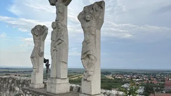Alte Steinskulpturen auf einer Mauer mit weitem Panoramablick über die ländliche Landschaft und ein Dorf.