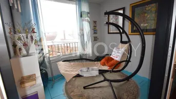 Gemütlicher Raum mit Hängesessel, großem Fenster und Zugang zu einem französischen Balkon.