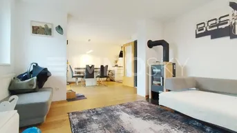 Geräumiger Wohn-Essbereich mit modernem Kaminofen und hellem Holzfußboden.