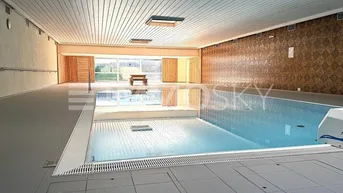 Großes Hallenbad mit Fliesenboden und Blick ins Grüne, ideal für Entspannung und Sport.