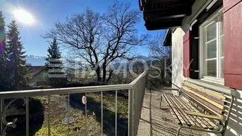 Sonniger Balkon mit Metallgeländer und Sitzbank, bietet einen weiten Blick auf die Berge und grüne Landschaft.