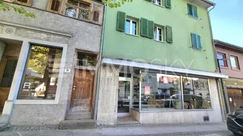 Fassade zweier angrenzender Gebäude mit traditionellen Holzläden und Ladenflächen im Erdgeschoss.