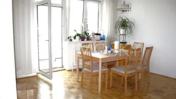 Heller Wohn- und Essbereich mit Parkettboden, Holztisch und Zugang zum Balkon.