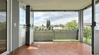 Helle Loggia mit Fliesenboden und weitem Blick ins Grüne und auf die Umgebung.