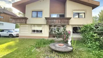 Traditionelles Einfamilienhaus mit zwei Balkonen, einem gepflegten Vorgarten und Satteldach.