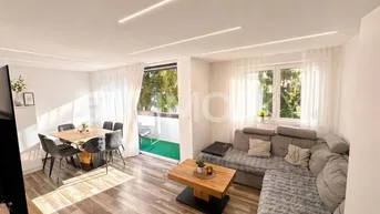 Helles Wohn- und Esszimmer mit modernem Sofa, Holzboden und Zugang zu einem kleinen Balkon.