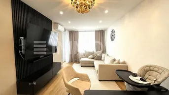 Modernes Wohnzimmer mit Holzboden, beigem Sofa und dekorativer Wandverkleidung.