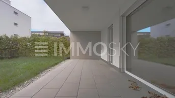 Große gepflasterte Terrasse mit angrenzender Rasenfläche und Hecke, ideal für Entspannung im Freien.