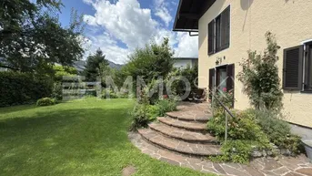 Großer gepflegter Garten mit Rasenfläche und Steintreppe, die zum Hauseingang führt.