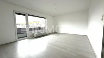 Helles, leeres Wohnzimmer mit modernem Laminatboden und großem Fenster mit Zugang nach draußen.