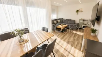 Heller offener Wohn- und Essbereich mit modernem Design, Holzboden und großen Fenstern.