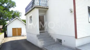 Außenansicht des Hauses mit Eingangsbereich, Rampe und separater Garage im Hintergrund.