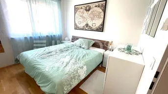 Helles Schlafzimmer mit Holzboden, großem Fenster und einem Weltkartenbild an der Wand.