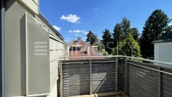 Geräumiger Balkon mit Holzboden und Blick auf die umliegenden Dächer und Bäume.