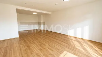 Helle, leere Küche mit Laminatboden und vorbereitetem Bereich für die Küchenzeile.