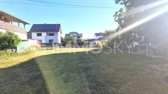 Sonniges Grundstück mit Rasenfläche und Blick auf umliegende Häuser.