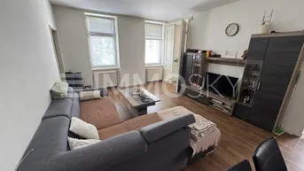 Gemütliches Wohnzimmer mit großem Ecksofa, Holzboden und Blick durch die Fenster.