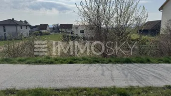 Blick auf ein unbebautes Grundstück mit angrenzender Straße und ländlicher Umgebung.