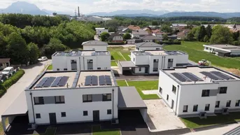 Luftaufnahme einer Siedlung mit modernen Neubauten und Photovoltaikanlagen auf den Dächern.