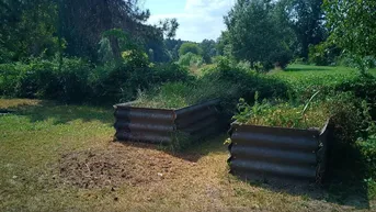 Naturbelassener Gartenbereich mit Hochbeeten und Blick ins Grüne.