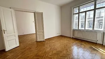 Helles, leeres Zimmer mit Fischgrätparkettboden und großen Fenstern, das viel Tageslicht hereinlässt.