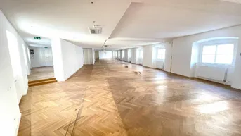 Großer, heller Raum mit Fischgrätparkett und vielen Fenstern, ideal für Büronutzung.