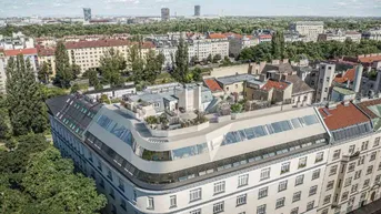 Luftaufnahme eines modernen Gebäudes mit Dachausbau und Stadtblick bei Tageslicht.