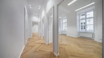 Heller Flur mit Fischgrätparkett, weißen Wänden und einem großen Spiegel, der einen weiteren Raum reflektiert.