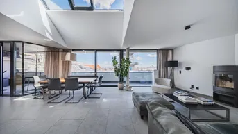 Heller Wohn- und Essbereich mit Dachfenstern, Kamin und weitem Stadtblick.