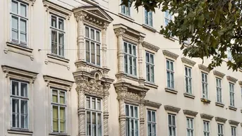 Detailansicht einer historischen Fassade mit reich verzierten Fenstern und Stuckelementen.
