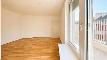 Helles, leeres Zimmer mit Parkettboden und Zugang zu einem Balkon, ideal als Wohnbereich.