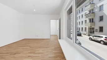 Helles, leeres Zimmer mit Parkettboden und Blick auf die Straße, bereit zur individuellen Gestaltung.