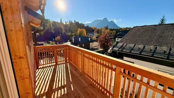 Sonnige Holzterrasse mit Bergblick und traditionellem Geländer, ideal zum Entspannen im Freien.