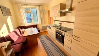 Funktionale Einbauküche mit Holzelementen, integriertem Essbereich und Fenster mit Blick ins Grüne.