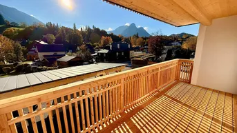Sonnenverwöhnter Balkon mit Holzboden und Geländer, bietet einen weiten Blick auf die umliegende Berglandschaft.
