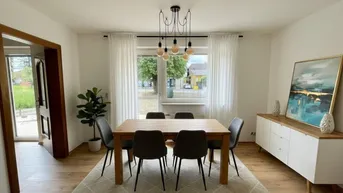 Helles Esszimmer mit Holztisch, modernen Stühlen und Blick ins Grüne durch das Fenster.