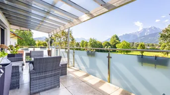 Große überdachte Terrasse mit modernen Gartenmöbeln und einem beeindruckenden Bergblick.