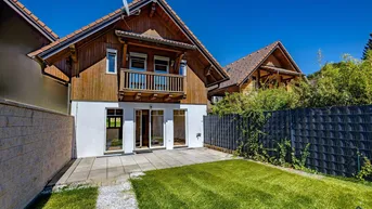 Charmantes Haus mit Holzfassade, kleinem Garten und sonniger Terrasse im Freien.