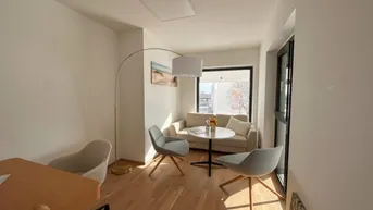 Heller und modern eingerichteter Wohnbereich mit beigem Sofa, zwei Sesseln und Holzboden, durchflutet von Tageslicht.