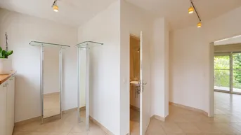 Heller Flur mit Fliesenboden, modernen Deckenspots und Zugang zu weiteren Räumen.