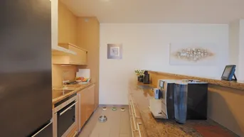 Funktionale Küche mit Granitarbeitsplatten, Holzschränken und modernen Geräten.