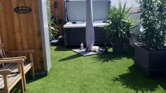 Geräumige Dachterrasse mit Kunstrasen, Whirlpool und Holzverkleidung, ideal zum Entspannen unter freiem Himmel.