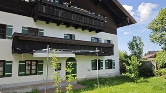 Traditionelles Haus mit Holzbalkonen, grünen Fensterläden und gepflegtem Vorgarten.