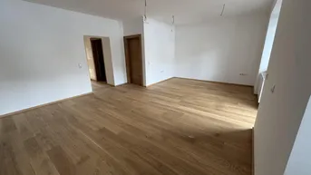 Heller, leerer Raum mit neuem Hartholzboden und weißen Wänden, bereit zum Einzug.