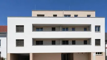 Modernes Mehrfamilienhaus mit weißer Fassade, integrierten Balkonen und Tiefgaragenzufahrt unter blauem Himmel.