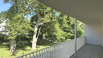 Geräumiger Balkon mit Fliesenboden und einem schönen Blick ins Grüne mit alten Bäumen.