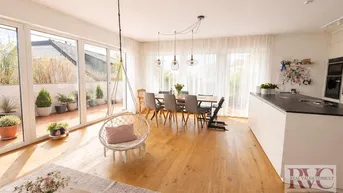Heller, offener Wohn- und Essbereich mit moderner Küche, Holzboden und Zugang zur sonnigen Terrasse.
