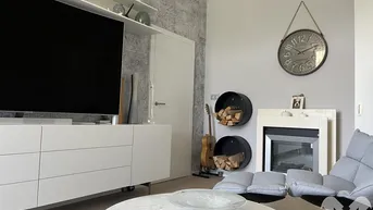 Wohnzimmer mit modernem Kamin, stilvoller Wanduhr und dekorativer Holzablage.