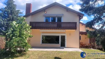 Vorderansicht eines Einfamilienhauses mit Balkon im Obergeschoss und einer kleinen Terrasse im Erdgeschoss.
