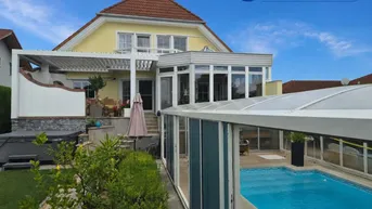 Großzügiger Außenbereich mit Hausfassade, überdachtem Pool und gepflegtem Garten.